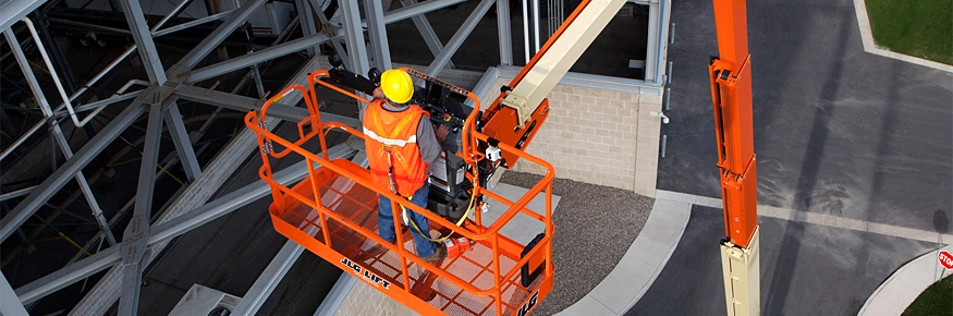 Plataforma telescópica JLG naranja operando en una construcción
